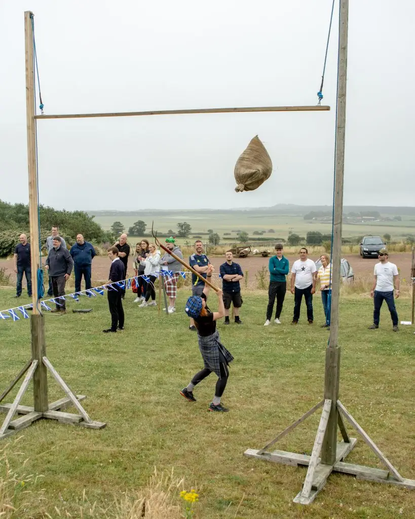 Participant taking part in Highland Games style activity at Wild Cairns
